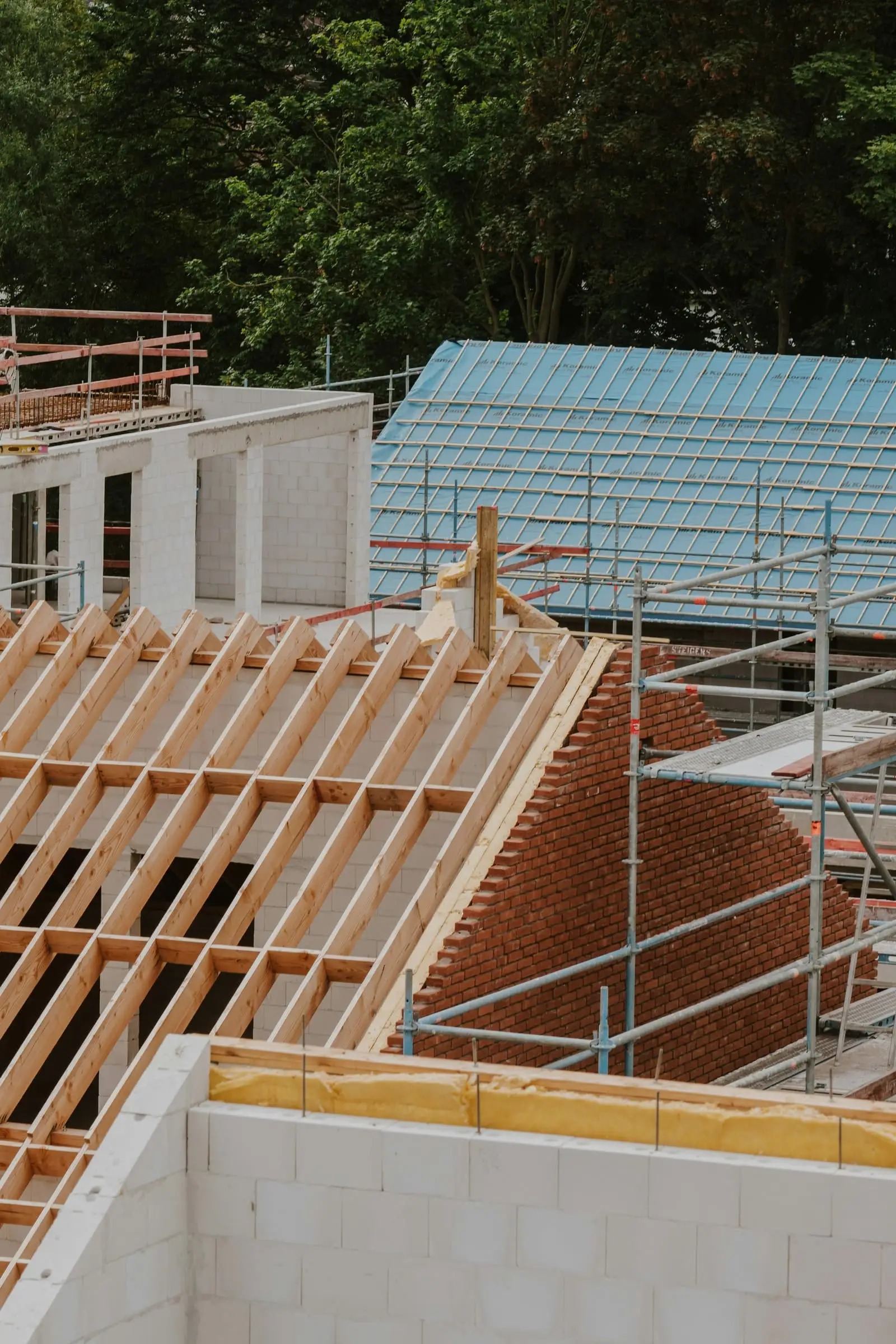 Nieuwe dakspanten op een bakstenen muur tijdens de ruwbouw