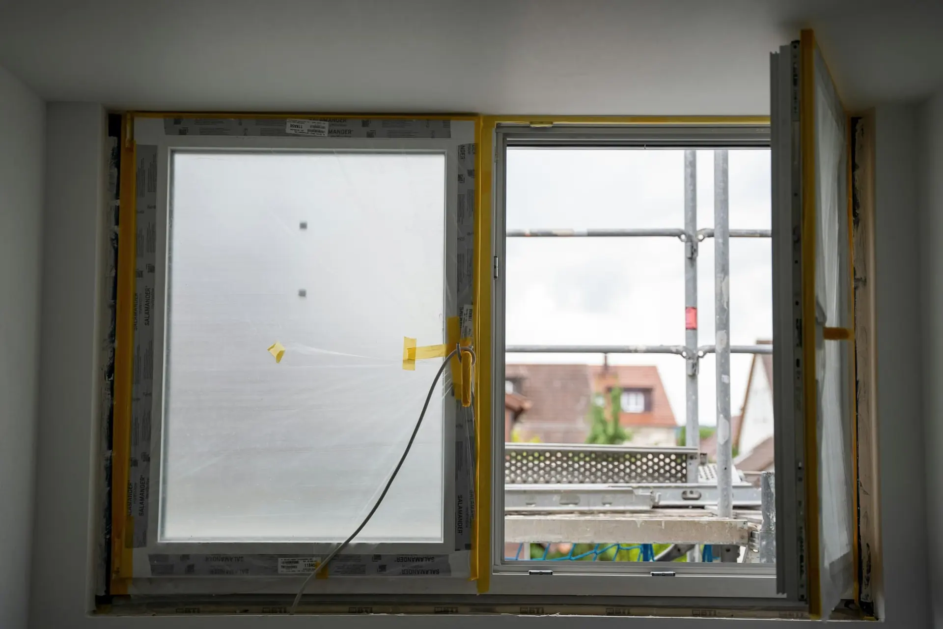 Nieuw raam tijdens de plaatsing, met stelling buiten en afgeplakte kozijnen