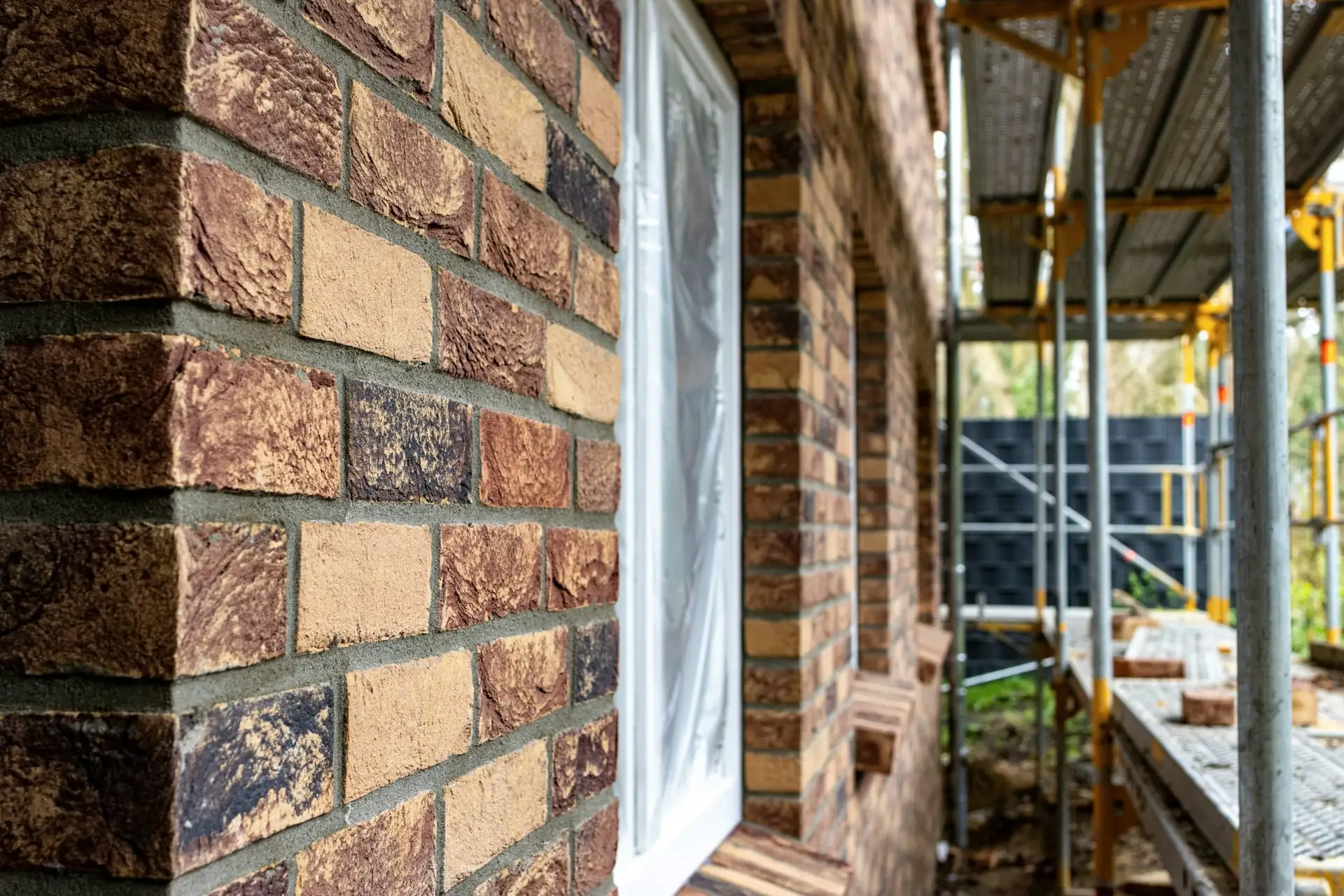 Oude baksteen en voegwerk in close-up naast een stelling