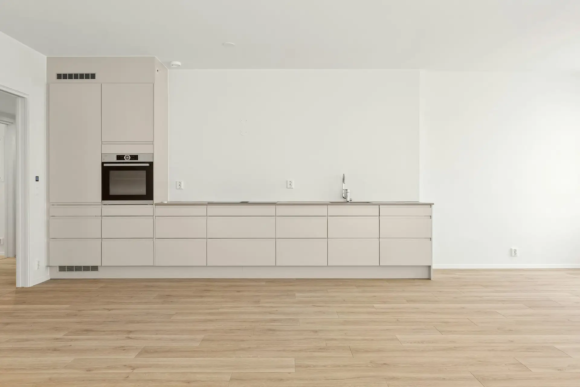Lege witte keukenwand met strakke kasten en eiken vloer