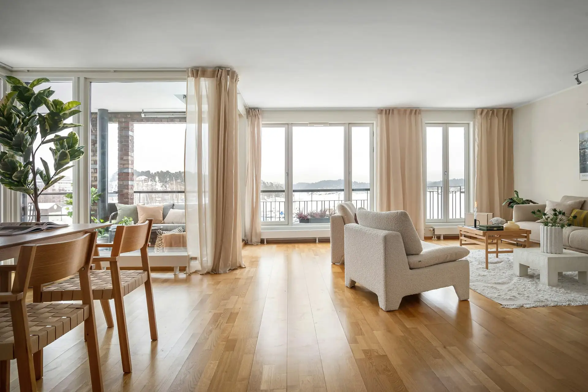Ingericht appartement met houten vloer, zitbank en eettafel aan het raam