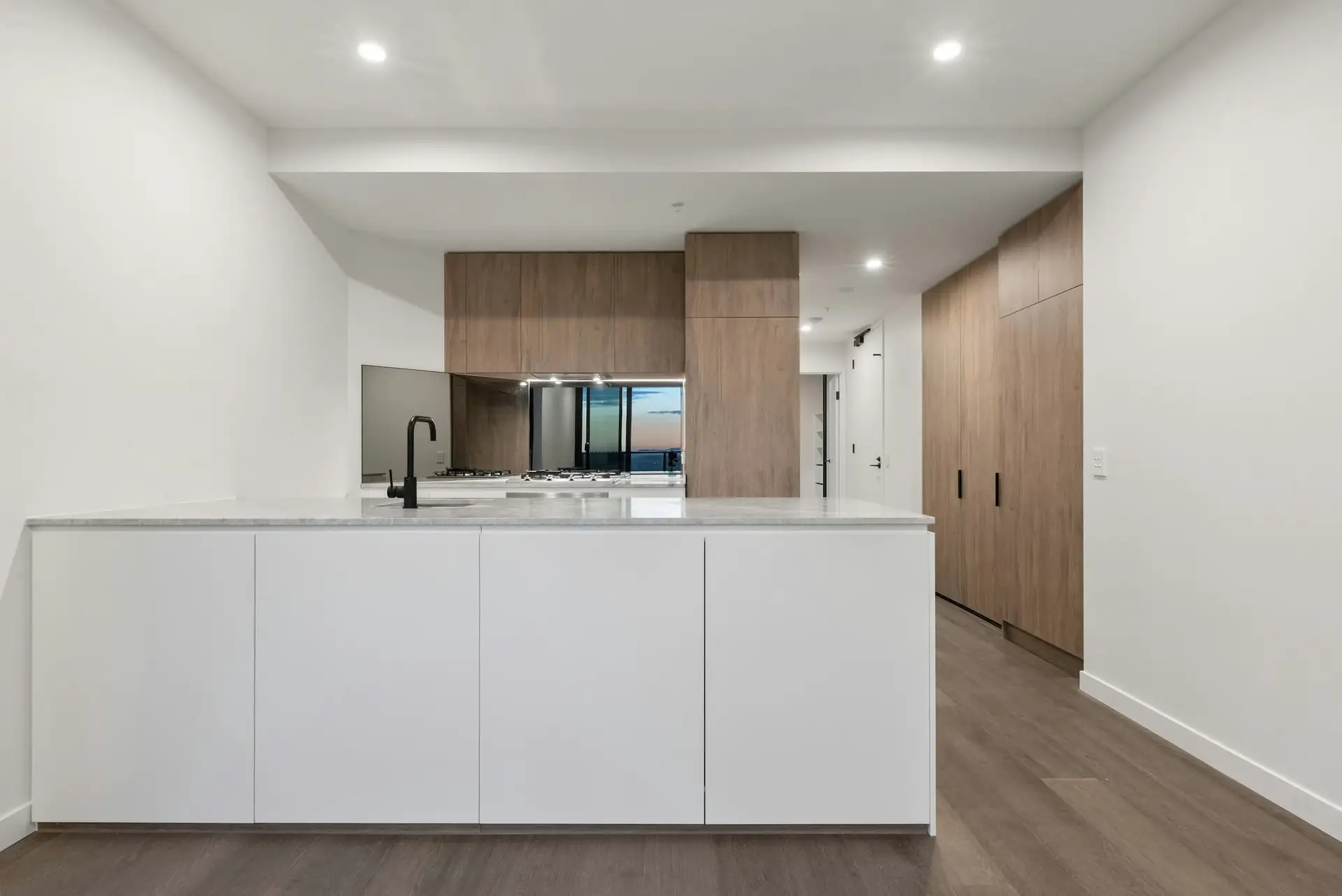 Witte keuken met eiland en donkere kastenwand
