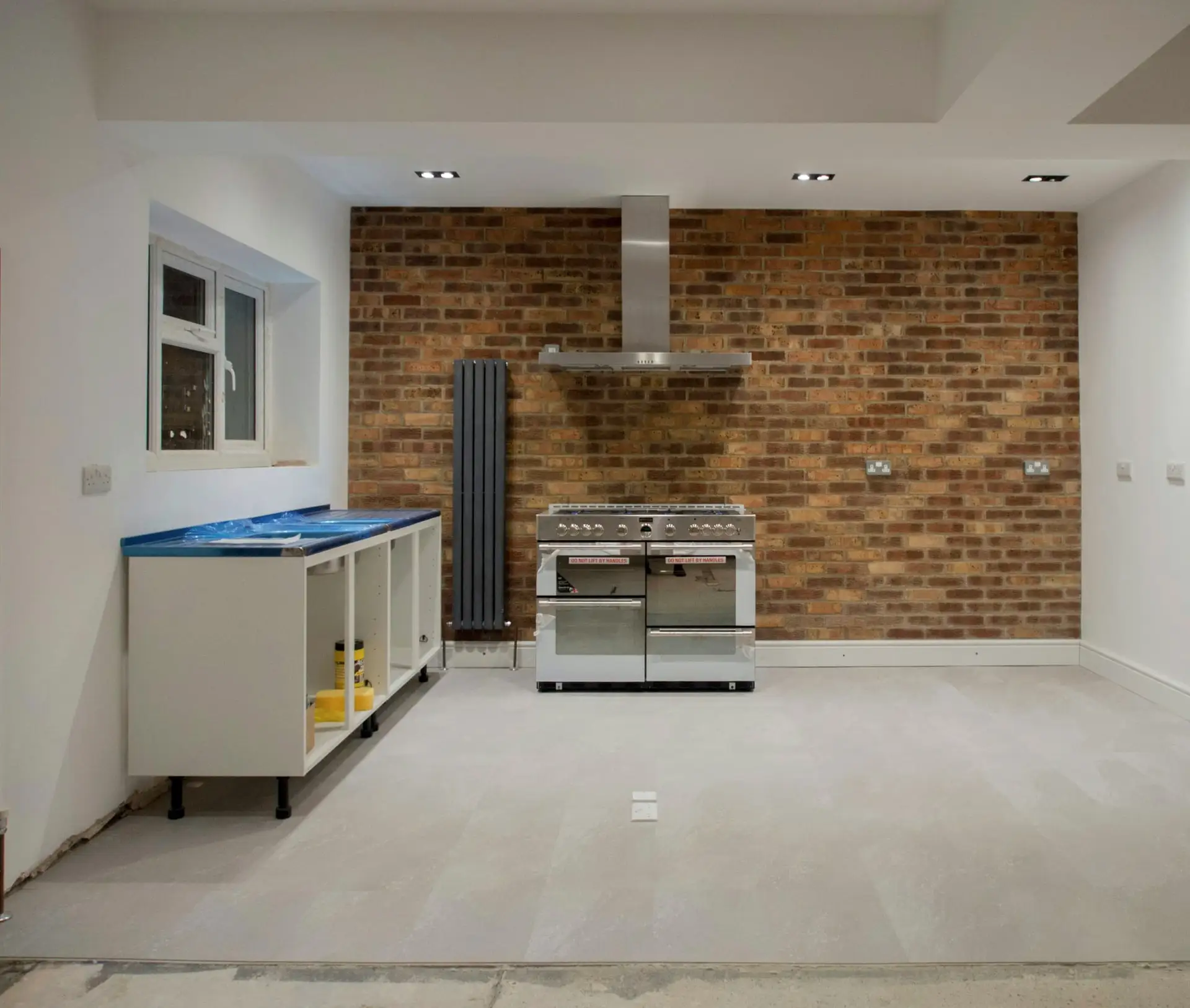 Dezelfde wand bij de afwerking: gereinigde baksteen, witte muren, ingebouwde spots en de keuken in plaatsing