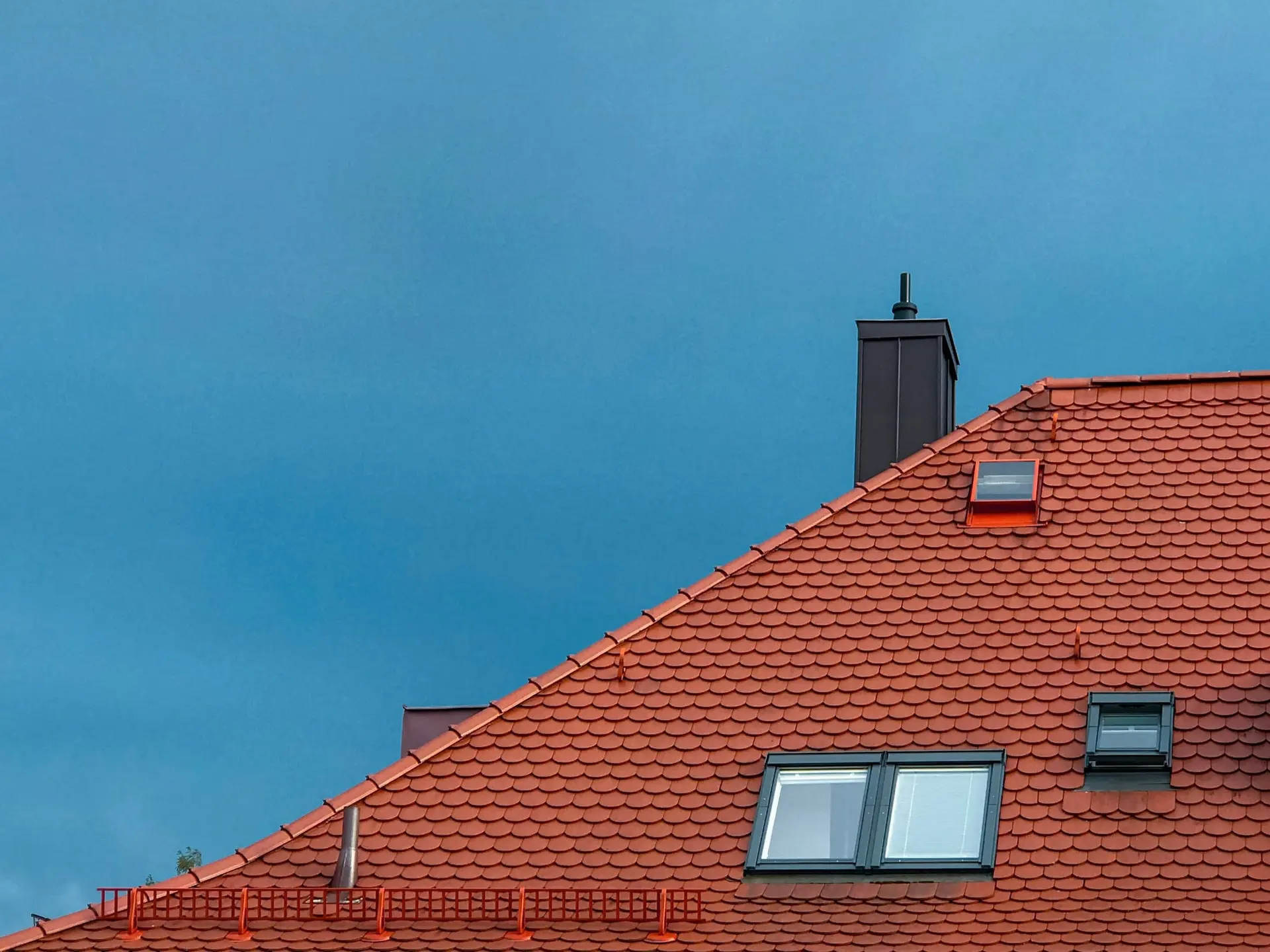Nieuw rood pannendak met dakvensters onder een blauwe lucht
